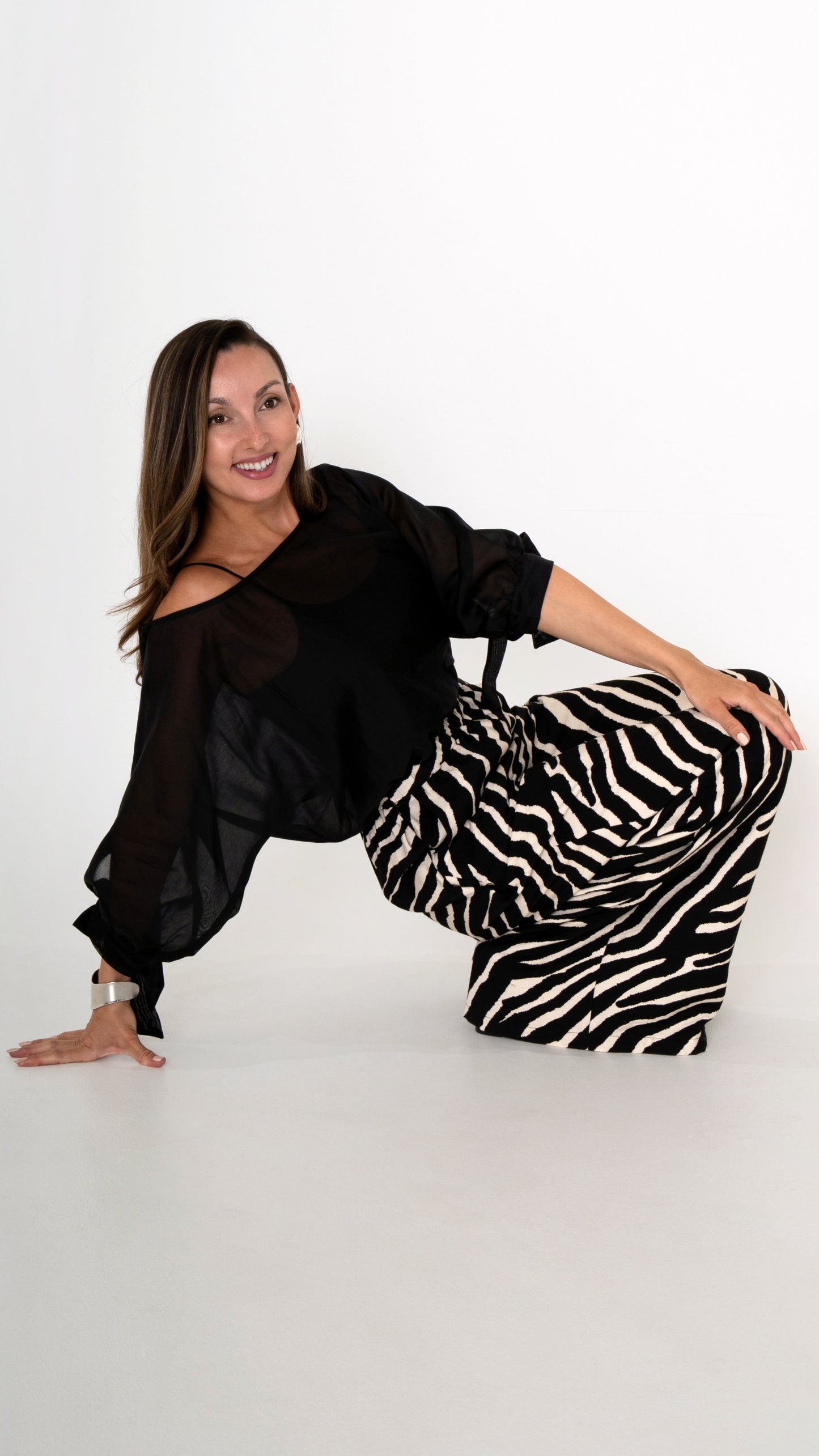 Fashion Editorial: elegante ausgefallene Damenbekleidung in schwarz weiß: Modisch sommerliches Outfit bestehend aus einer weiten Zebra Print Hose und einer schwarzen Volumen Chiffonbluse mit Schleifen am Ärmel
