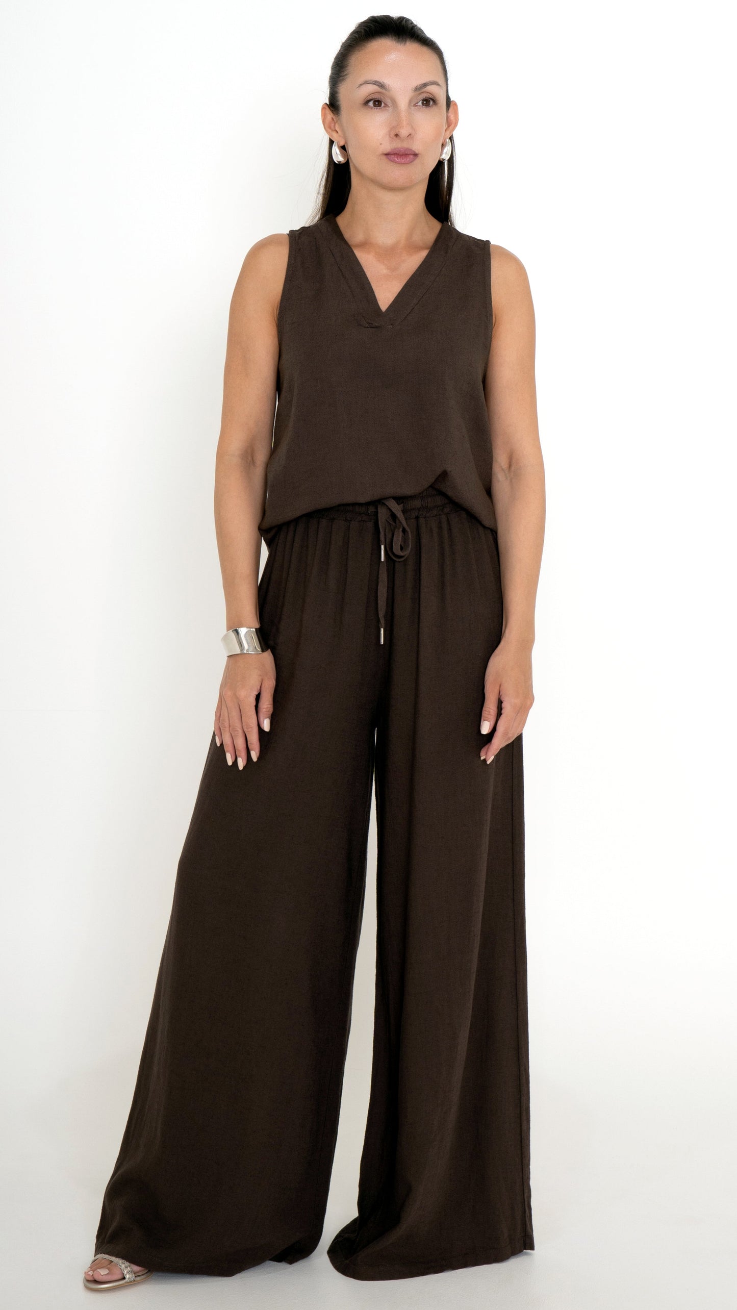 Feminine Damenmode für den Sommer in Mocca Braun: Model trägt ein braunes Outfit aus Leinen bestehend aus einer weiten Stoffhose und einem farblich passenden Top mit V-Ausschnit, ärmellos.